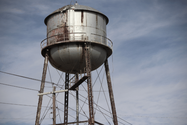 Aging elevated water storage tank showing visible rust, symbolizing infrastructure risks to water security.