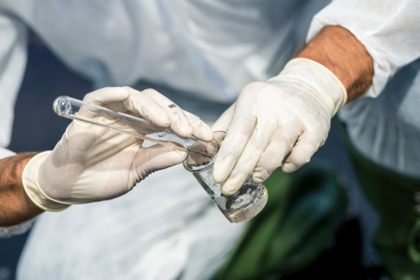 Technician collecting water sample in the field for water quality monitoring and analysis